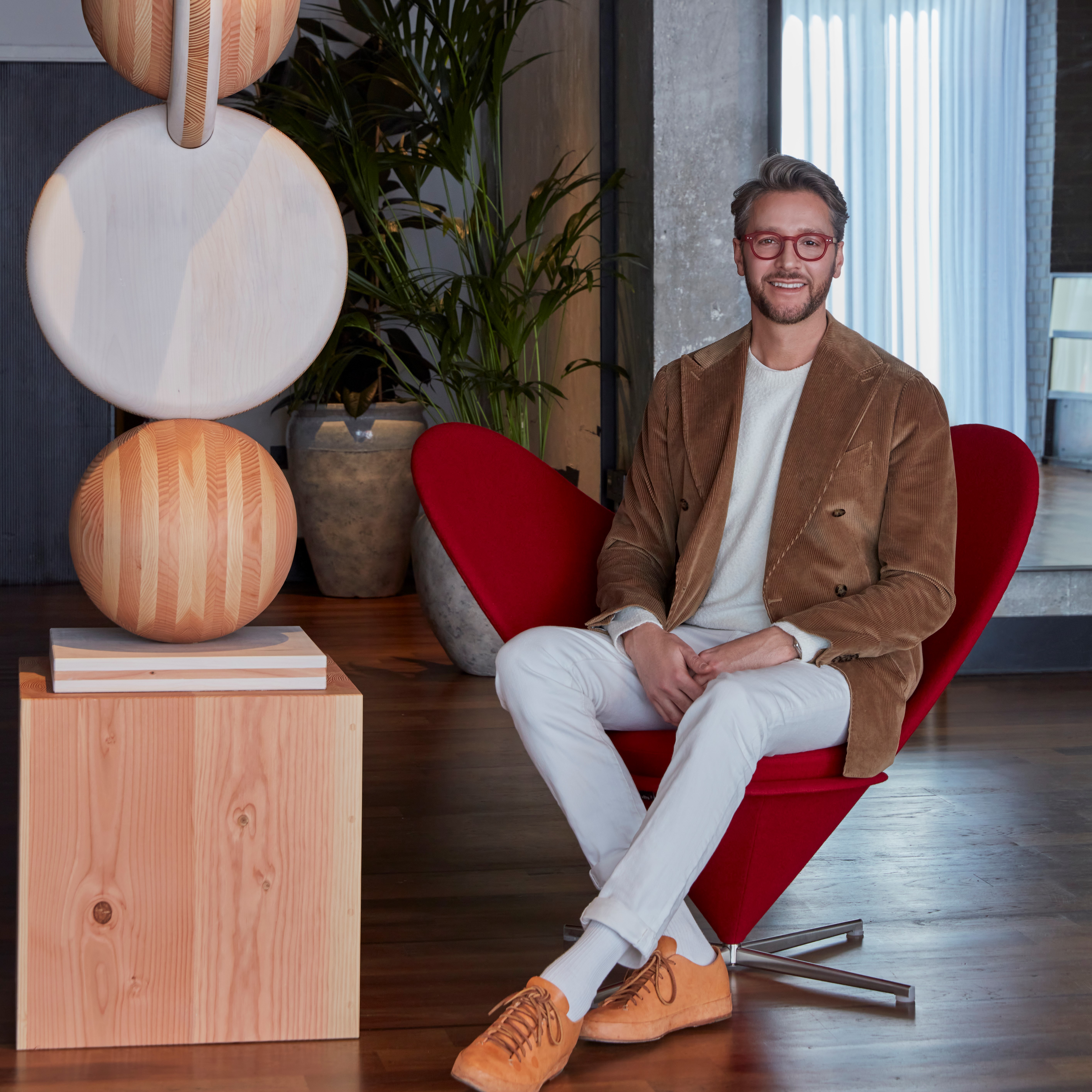 Professional photo of Jacu Strauss sitting in a red designer armchair.