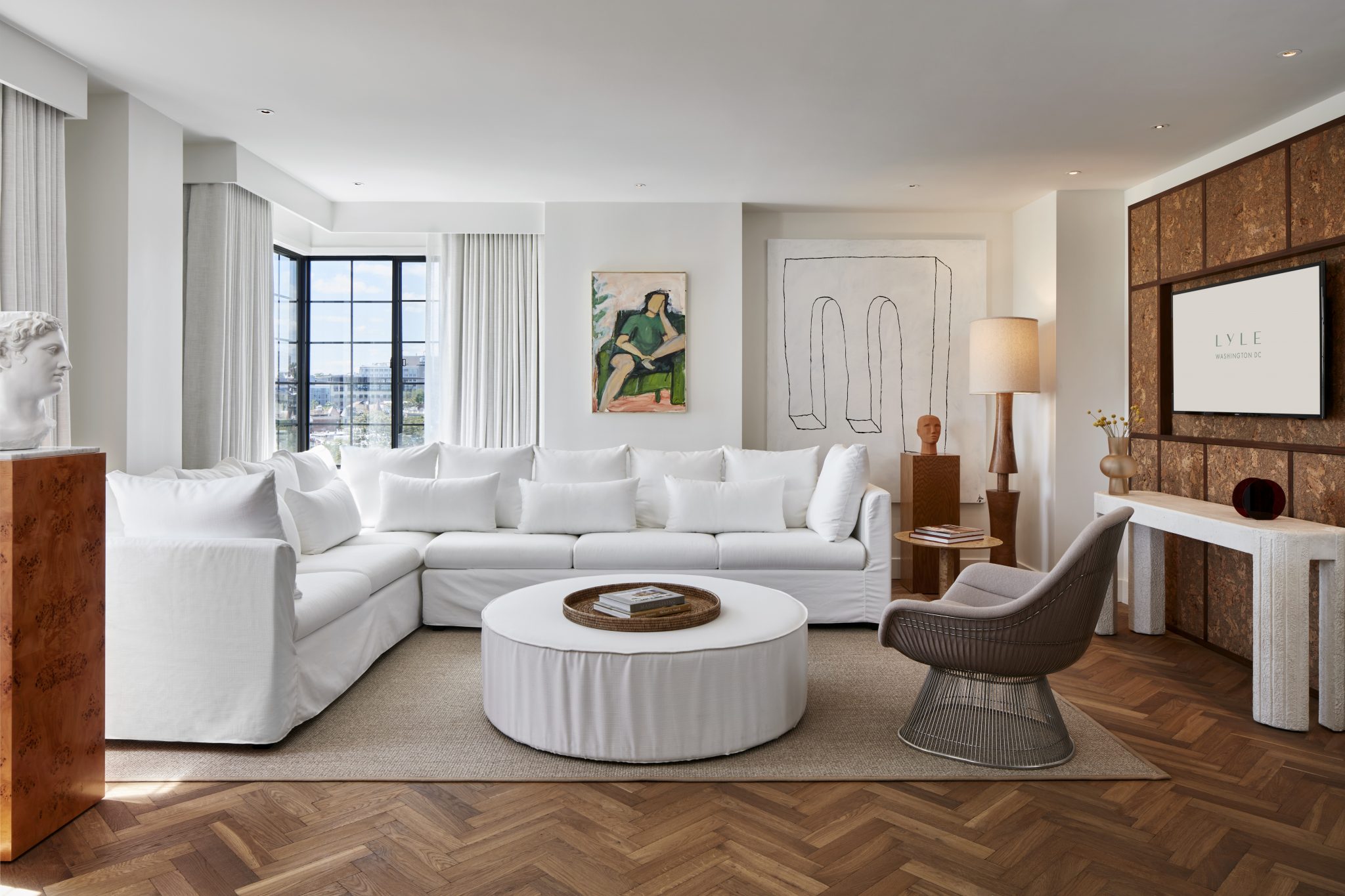 Bright, contemporary living room in a Lyle Suite featuring a large white sofa, modern art, and panoramic city views.