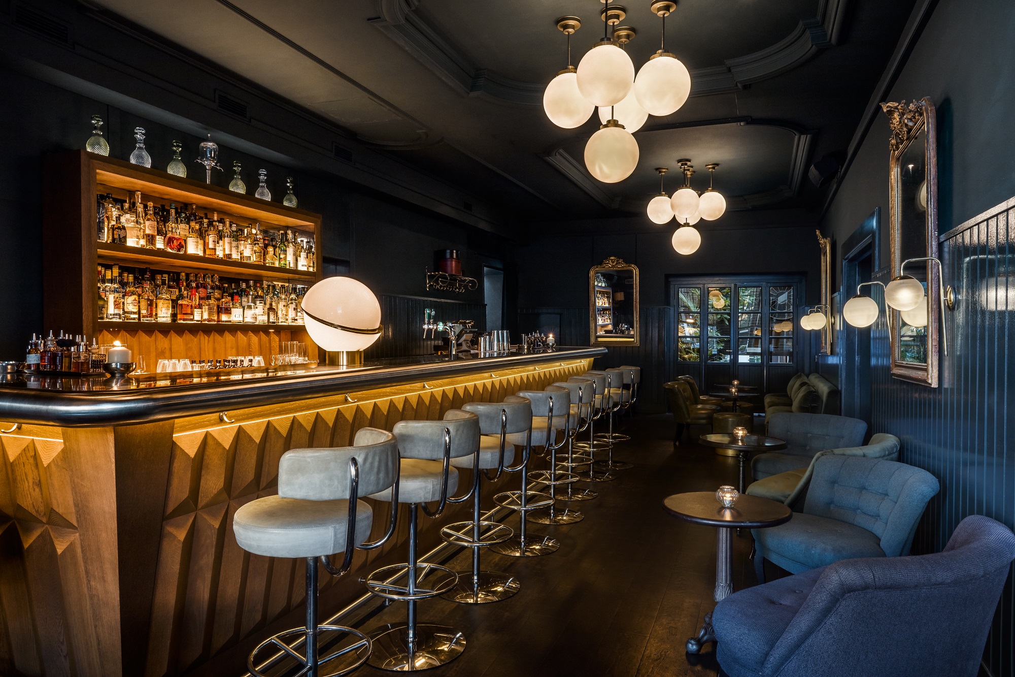 A sophisticated hotel bar with dark wood accents, plush seating, and warm lighting.