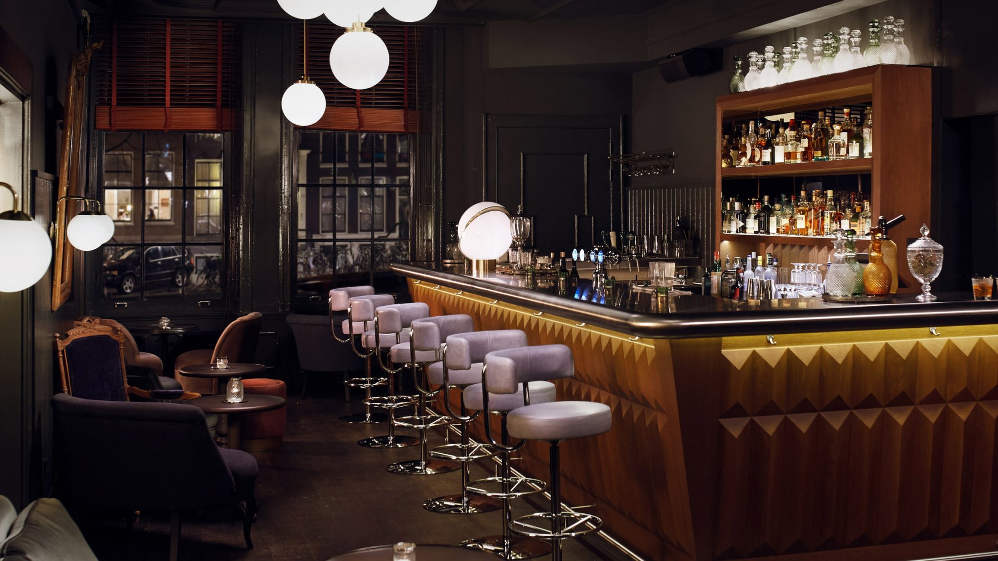 Cozy, upscale bar with plush seating, warm lighting, and a well-stocked bar, creating an intimate evening ambiance.