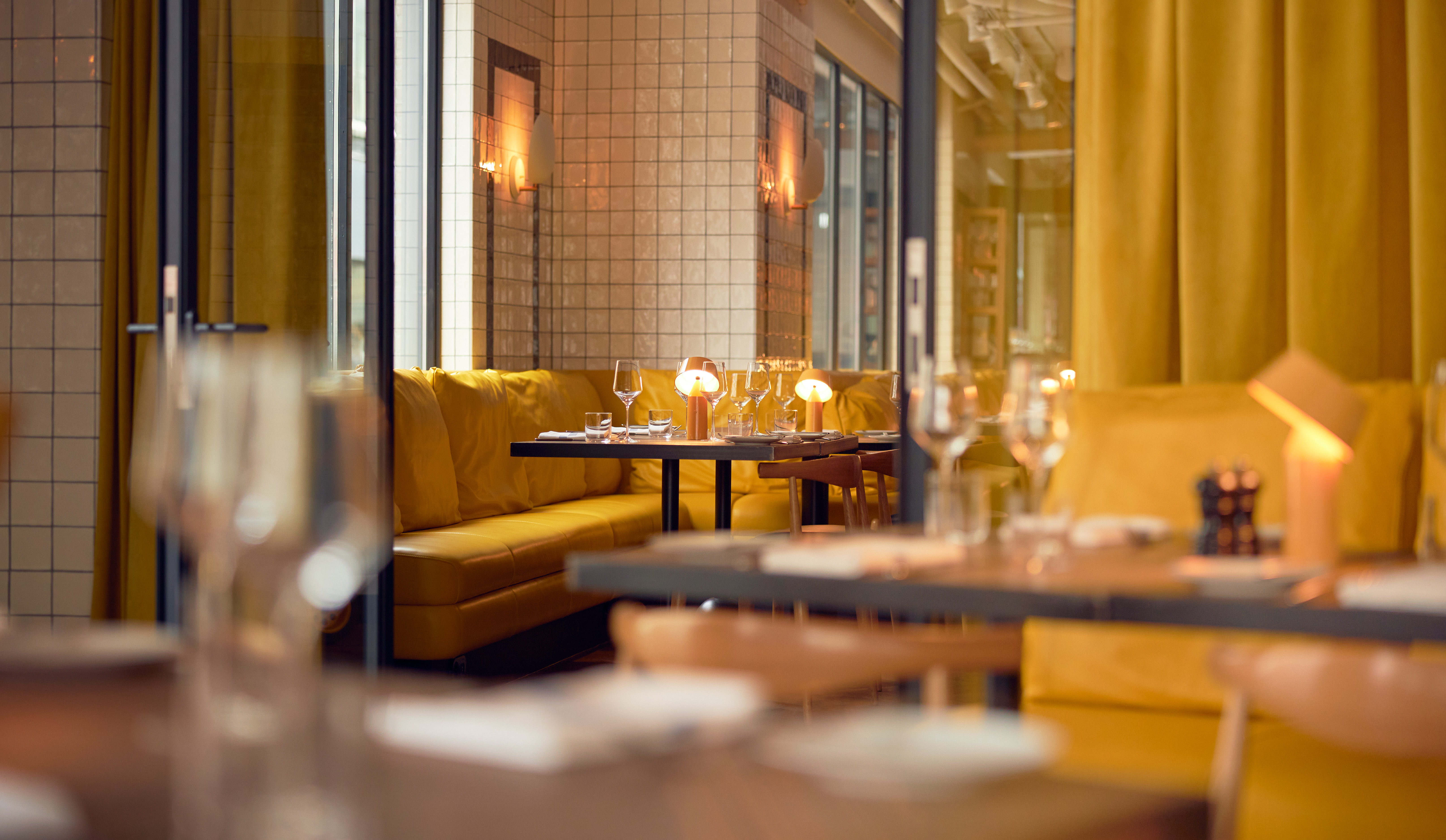 Intimate dining area with yellow seating, warm lighting, and a cosy ambiance, perfect for a private meal.