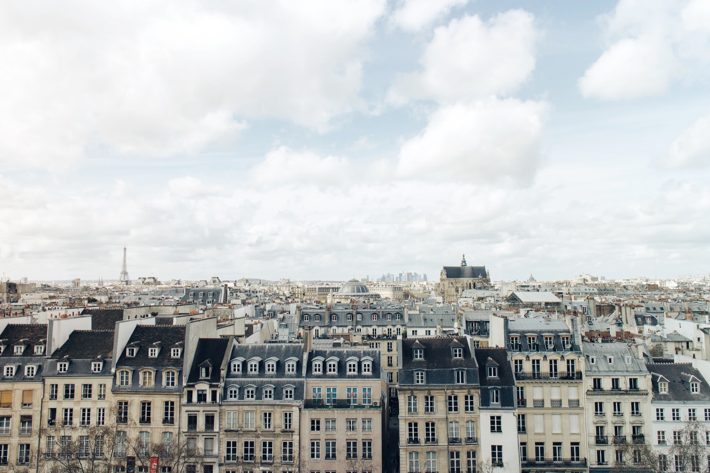 Aerial view of a cityscape in Paris with a prominent central building under a cloudy sky.