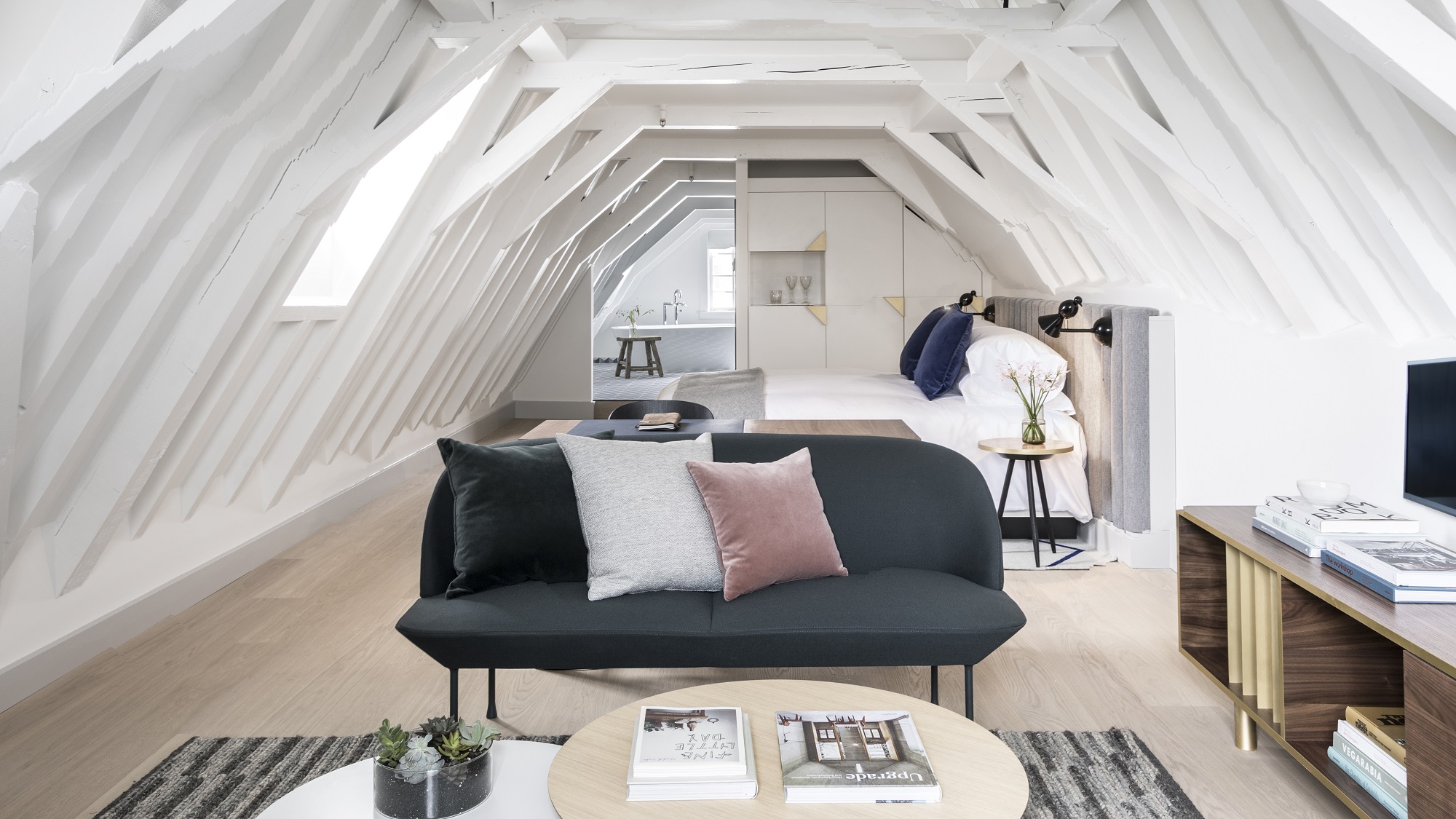 A spacious hotel room with a king-sized bed, modern furnishings, and large windows.