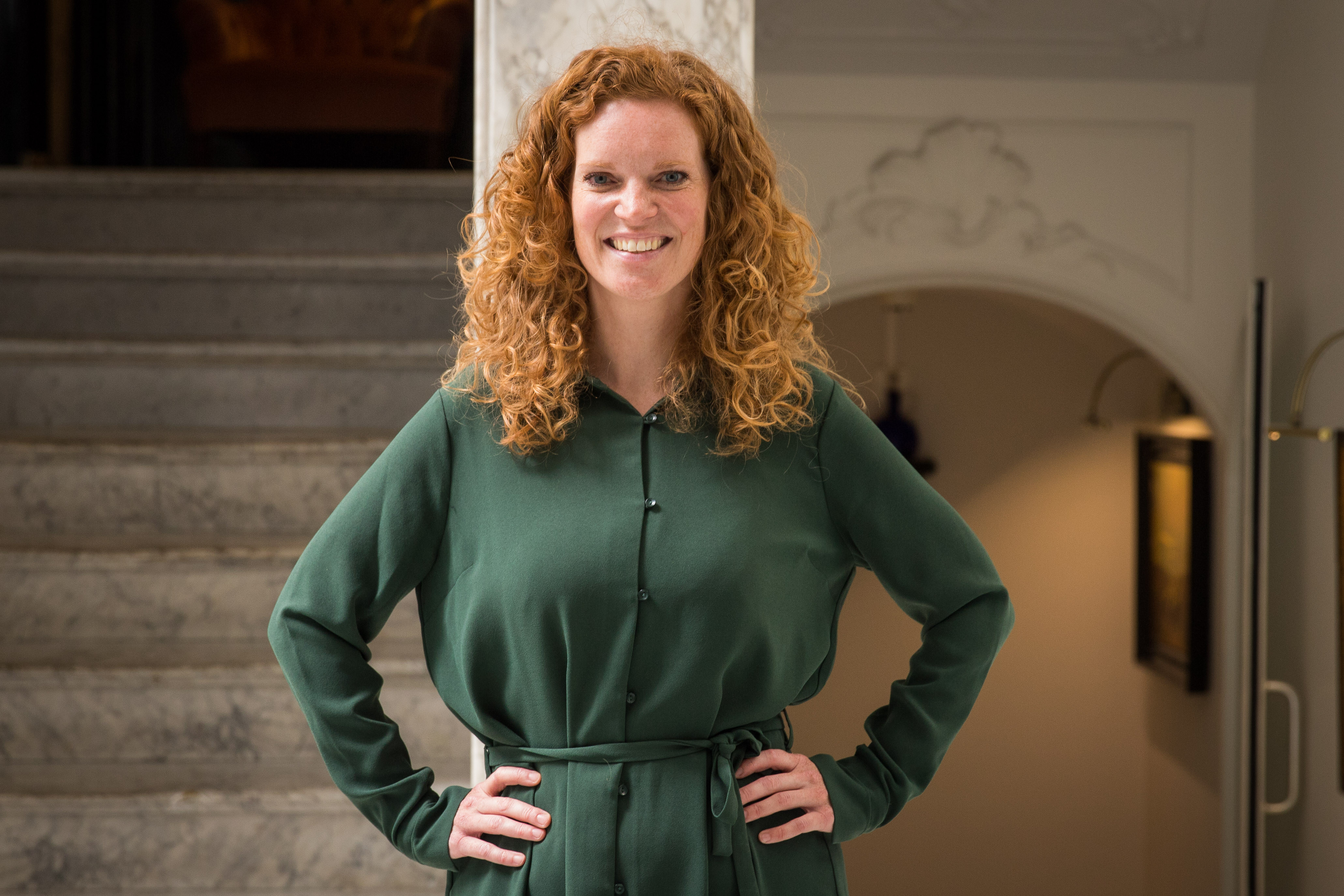 Classic hotel reception with a vintage-style clock, wooden counter, and ornate light fixtures, welcoming guests in style.