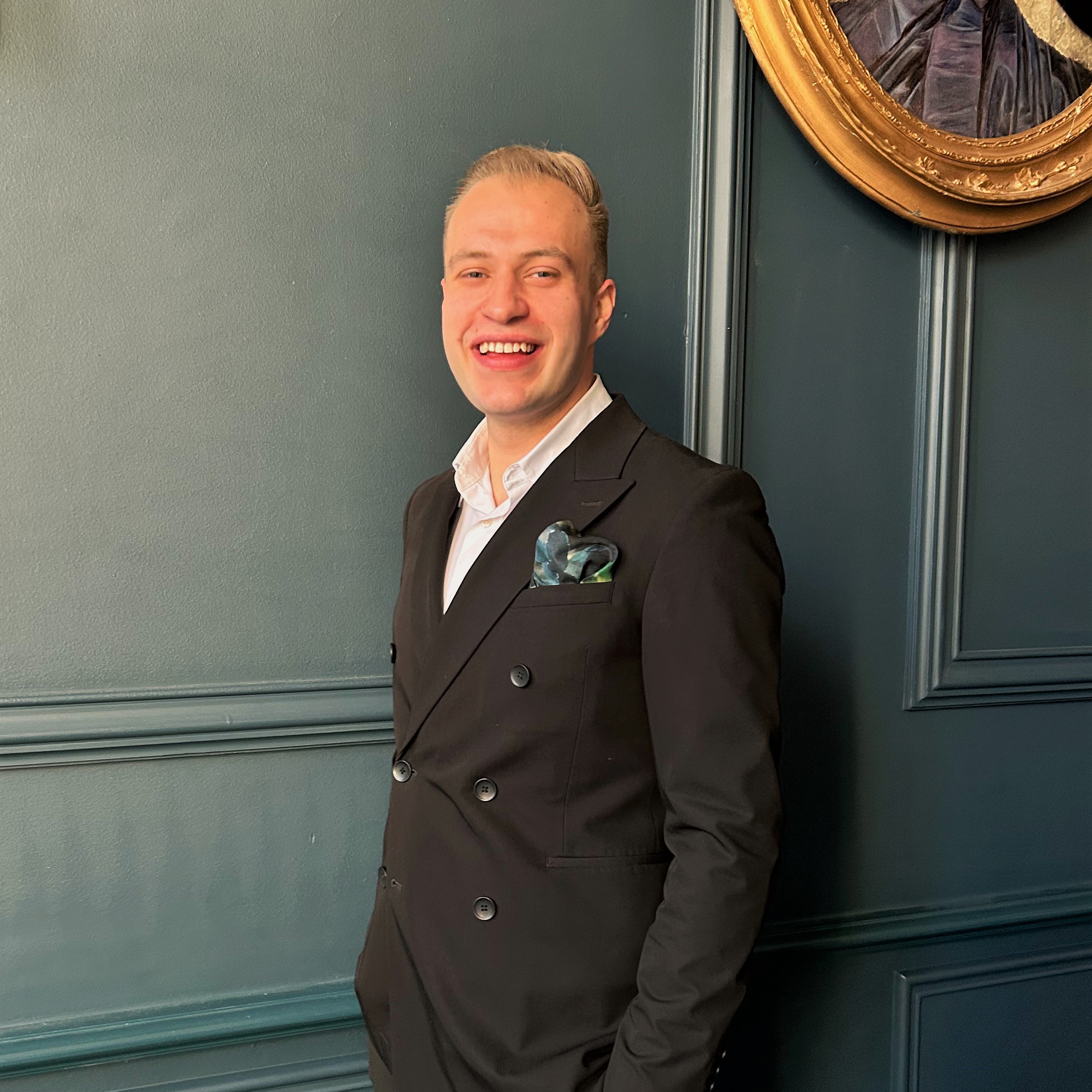A professional portrait of Maciej, confidently smiling in a contemporary, well-lit interior.