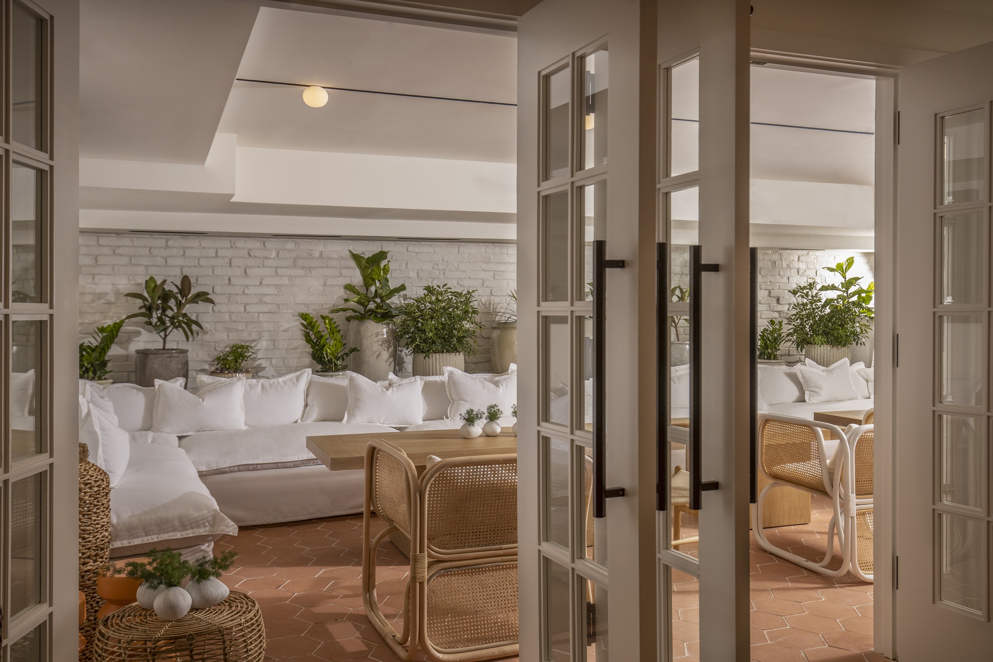 A bright white room adorned with white furniture and lush green plants, creating a serene and minimalist atmosphere.