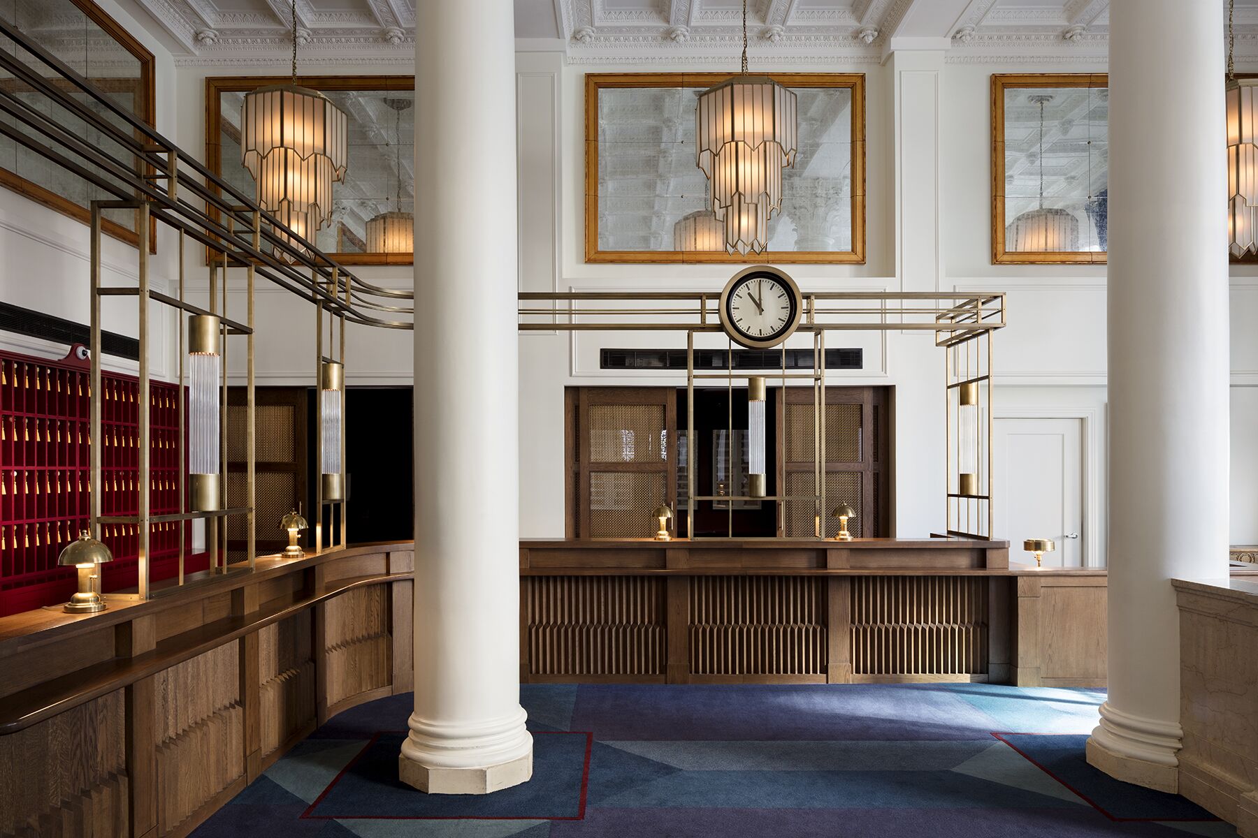 Beautiful wooden reception desk area at Riggs DC in Washington with a marble column and a large clock.