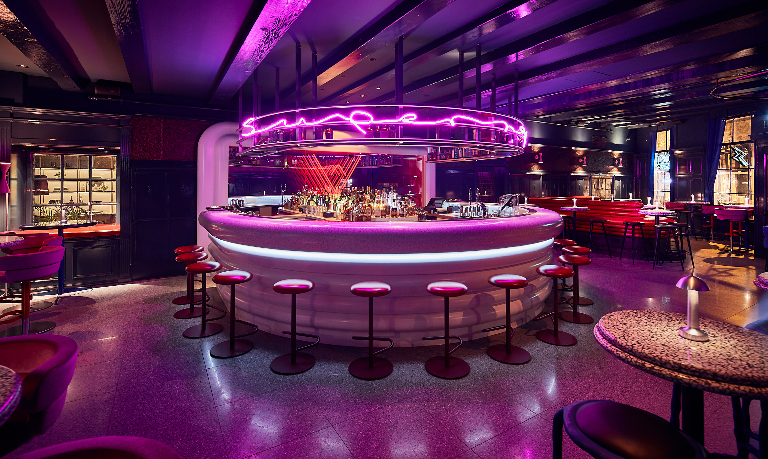 A vibrant bar with contemporary seating, ambient lighting, and a lively atmosphere.
