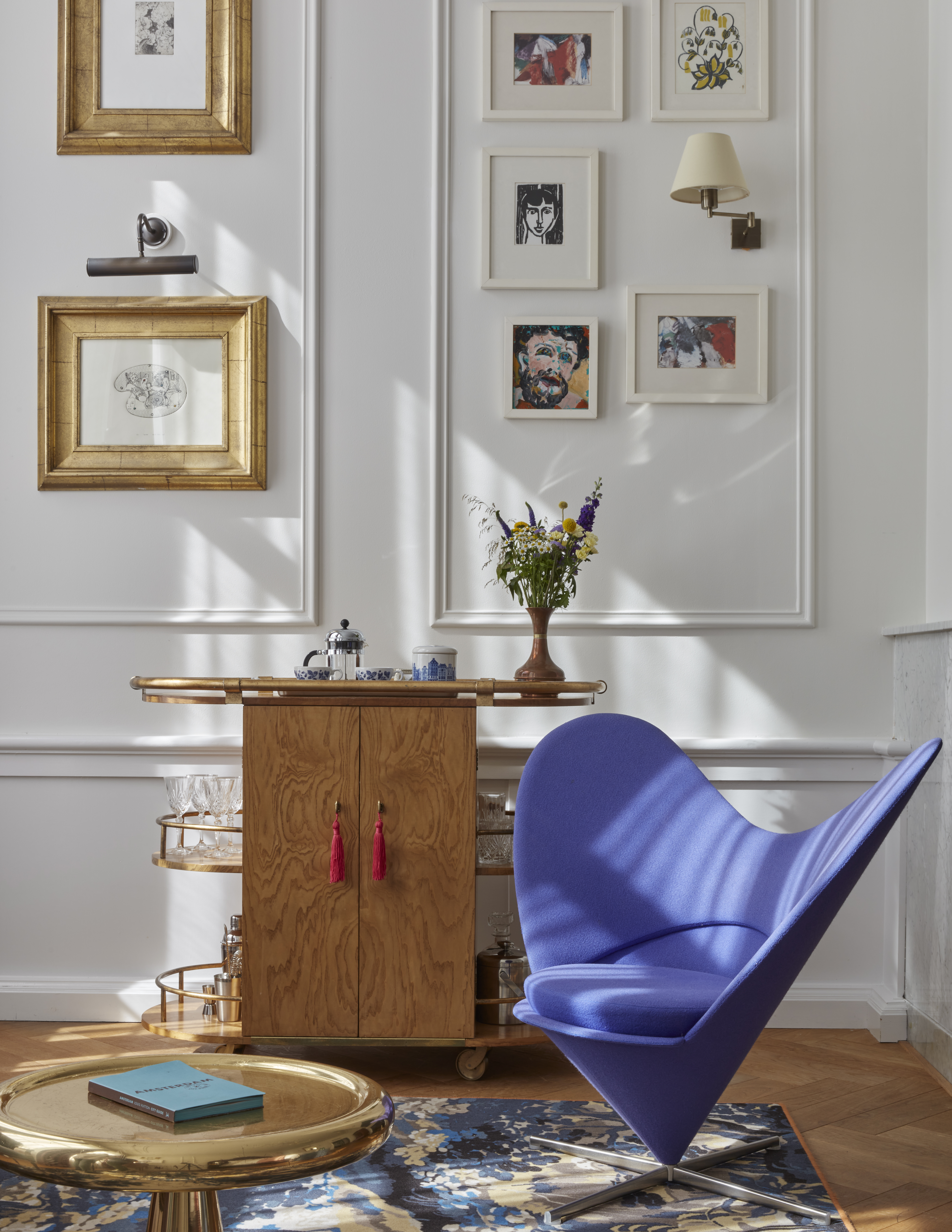 A blue chair positioned in front of a wall adorned with various pictures, creating a cozy and artistic atmosphere.