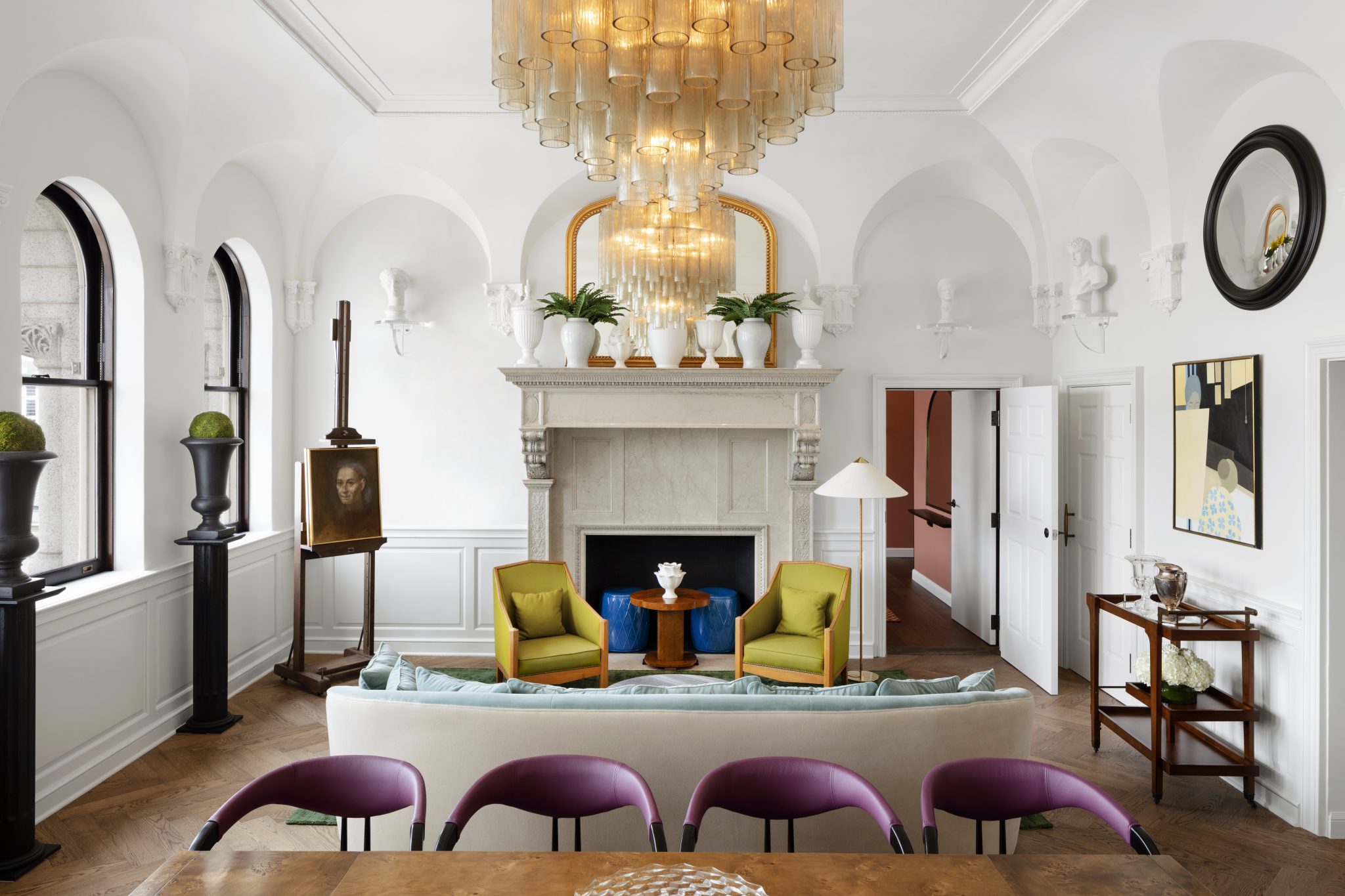 Luxurious suite with a cozy fireplace, chic armchairs, and an elegant chandelier hanging above a spacious living area.