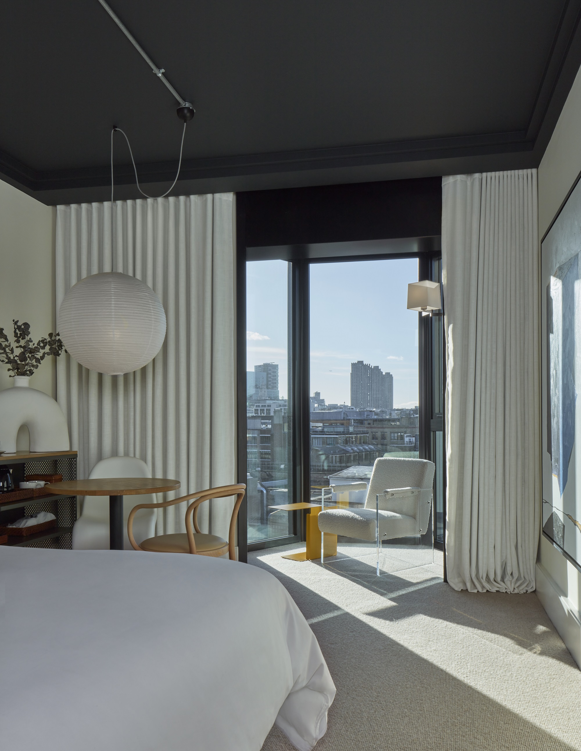 Beautifully lit corner of a modern hotel room showcasing the unique design of Lore Group and a city centre view to London.
